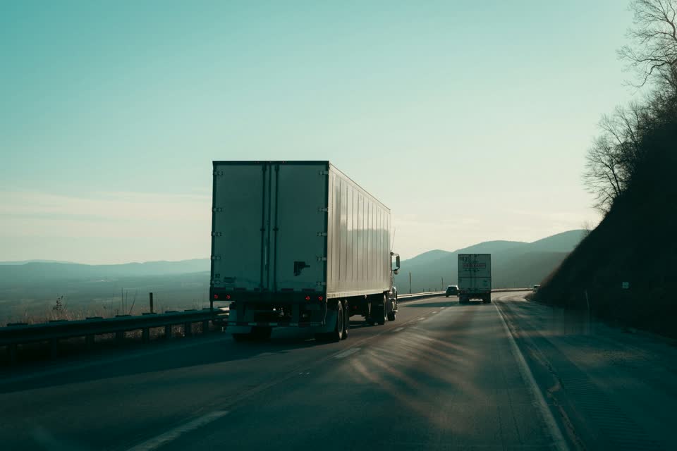 Two trucks on a highway climbing into the hills